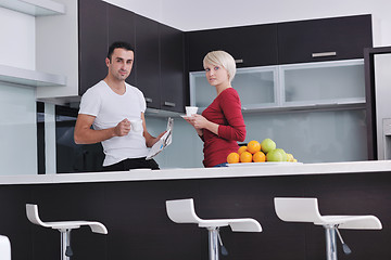 Image showing Happy couple reading the newspaper in the kitchen at breakfast