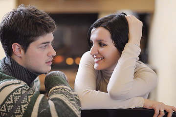 Image showing Young romantic couple sitting and relaxing in front of fireplace