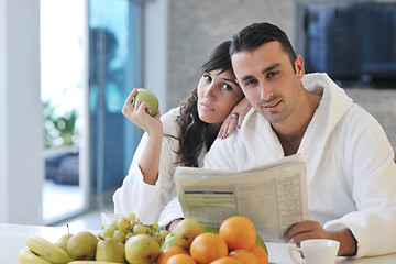 Image showing Happy couple reading the newspaper in the kitchen at breakfast