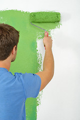 Image showing handsome young man paint white wall in color