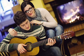 Image showing Young romantic couple sitting on sofa in front of fireplace at h