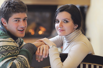 Image showing Young romantic couple sitting and relaxing in front of fireplace