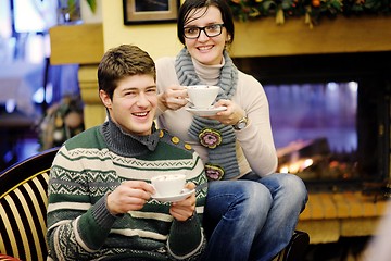 Image showing Young romantic couple sitting on sofa in front of fireplace at h