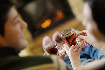 Image showing Young romantic couple sitting on sofa in front of fireplace at h