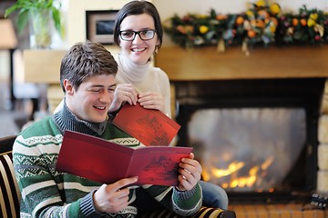 Image showing Young romantic couple relax on sofa in front of fireplace at hom