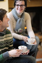 Image showing Young romantic couple sitting on sofa in front of fireplace at h