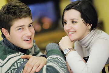 Image showing Young romantic couple sitting on sofa in front of fireplace at h