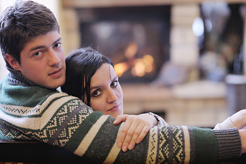 Image showing Young romantic couple sitting and relaxing in front of fireplace