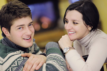 Image showing Young romantic couple sitting and relaxing in front of fireplace