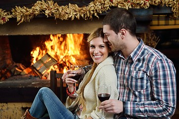 Image showing Young romantic couple sitting on sofa in front of fireplace at h