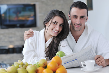 Image showing Happy couple reading the newspaper in the kitchen at breakfast