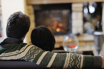 Image showing Young romantic couple sitting and relaxing in front of fireplace