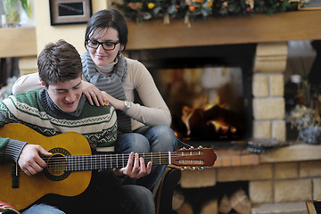 Image showing Young romantic couple sitting and relaxing in front of fireplace