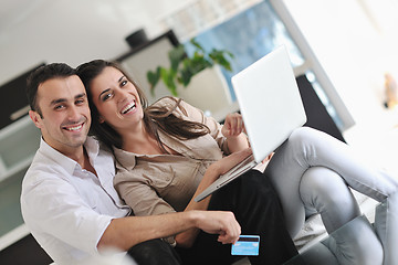 Image showing joyful couple relax and work on laptop computer at modern home