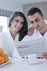 Image showing Happy couple reading the newspaper in the kitchen at breakfast