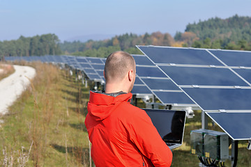 Image showing engineer using laptop at solar panels plant field