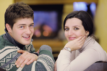 Image showing Young romantic couple sitting and relaxing in front of fireplace