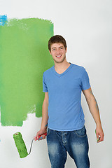 Image showing handsome young man paint white wall in color