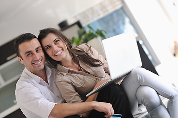 Image showing joyful couple relax and work on laptop computer at modern home