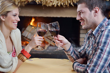 Image showing Young romantic couple sitting and relaxing in front of fireplace