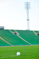 Image showing Soccer ball on grass at goal and stadium in background