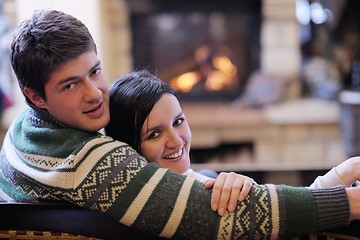 Image showing Young romantic couple sitting on sofa in front of fireplace at h