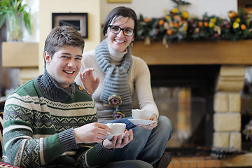 Image showing Young romantic couple sitting and relaxing in front of fireplace