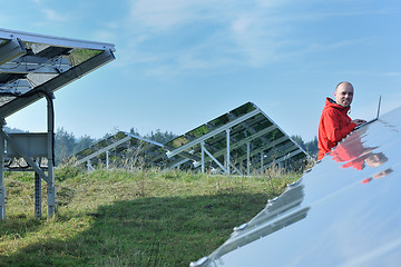 Image showing engineer using laptop at solar panels plant field