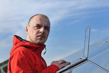 Image showing engineer using laptop at solar panels plant field