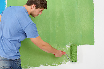 Image showing handsome young man paint white wall in color