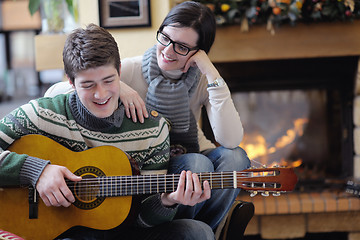 Image showing Young romantic couple sitting and relaxing in front of fireplace