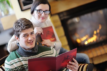 Image showing Young romantic couple relax on sofa in front of fireplace at hom