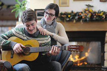 Image showing Young romantic couple sitting and relaxing in front of fireplace