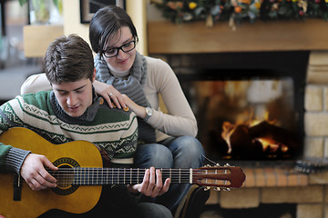 Image showing Young romantic couple sitting and relaxing in front of fireplace