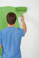 Image showing handsome young man paint white wall in color