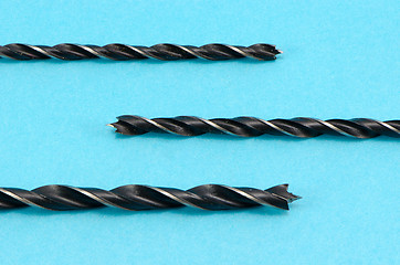 Image showing closeup of metal drill bits for wood on blue 