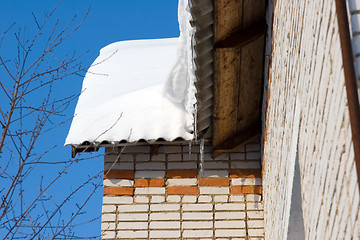 Image showing Snow covered roof with icicles