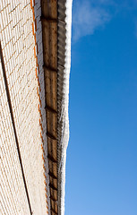 Image showing Snow covered roof with icicles, deep blue sky at background
