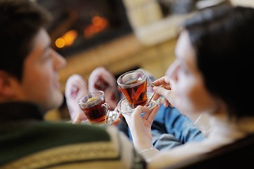 Image showing Young romantic couple relax on sofa in front of fireplace at hom