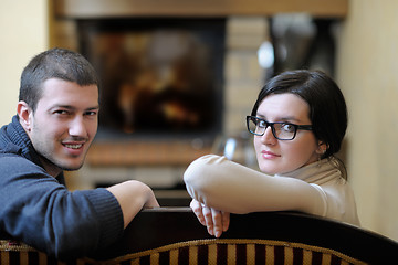 Image showing Young romantic couple sitting and relaxing in front of fireplace