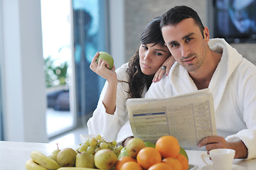 Image showing Happy couple reading the newspaper in the kitchen at breakfast