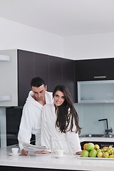 Image showing Happy couple reading the newspaper in the kitchen at breakfast