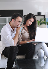 Image showing joyful couple relax and work on laptop computer at modern home