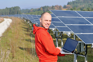 Image showing engineer using laptop at solar panels plant field