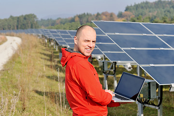 Image showing engineer using laptop at solar panels plant field