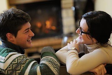 Image showing Young romantic couple sitting on sofa in front of fireplace at h