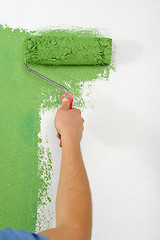 Image showing handsome young man paint white wall in color