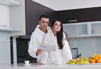 Image showing Happy couple reading the newspaper in the kitchen at breakfast