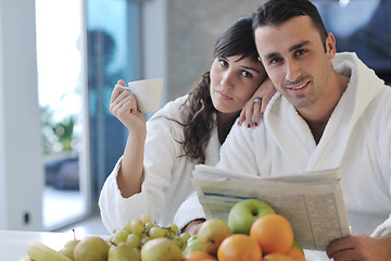 Image showing Happy couple reading the newspaper in the kitchen at breakfast