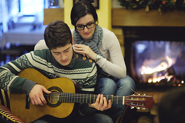 Image showing Young romantic couple sitting and relaxing in front of fireplace